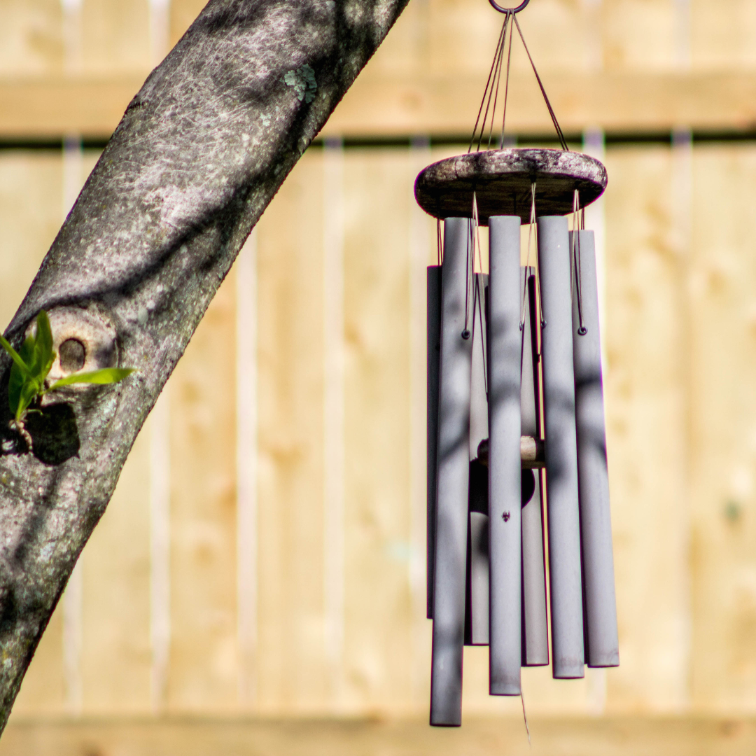 Red barn with white trim, doors, and window against a backdrop of green trees.