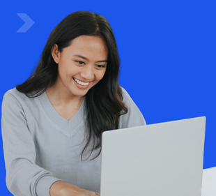A woman is smiling while using a laptop computer