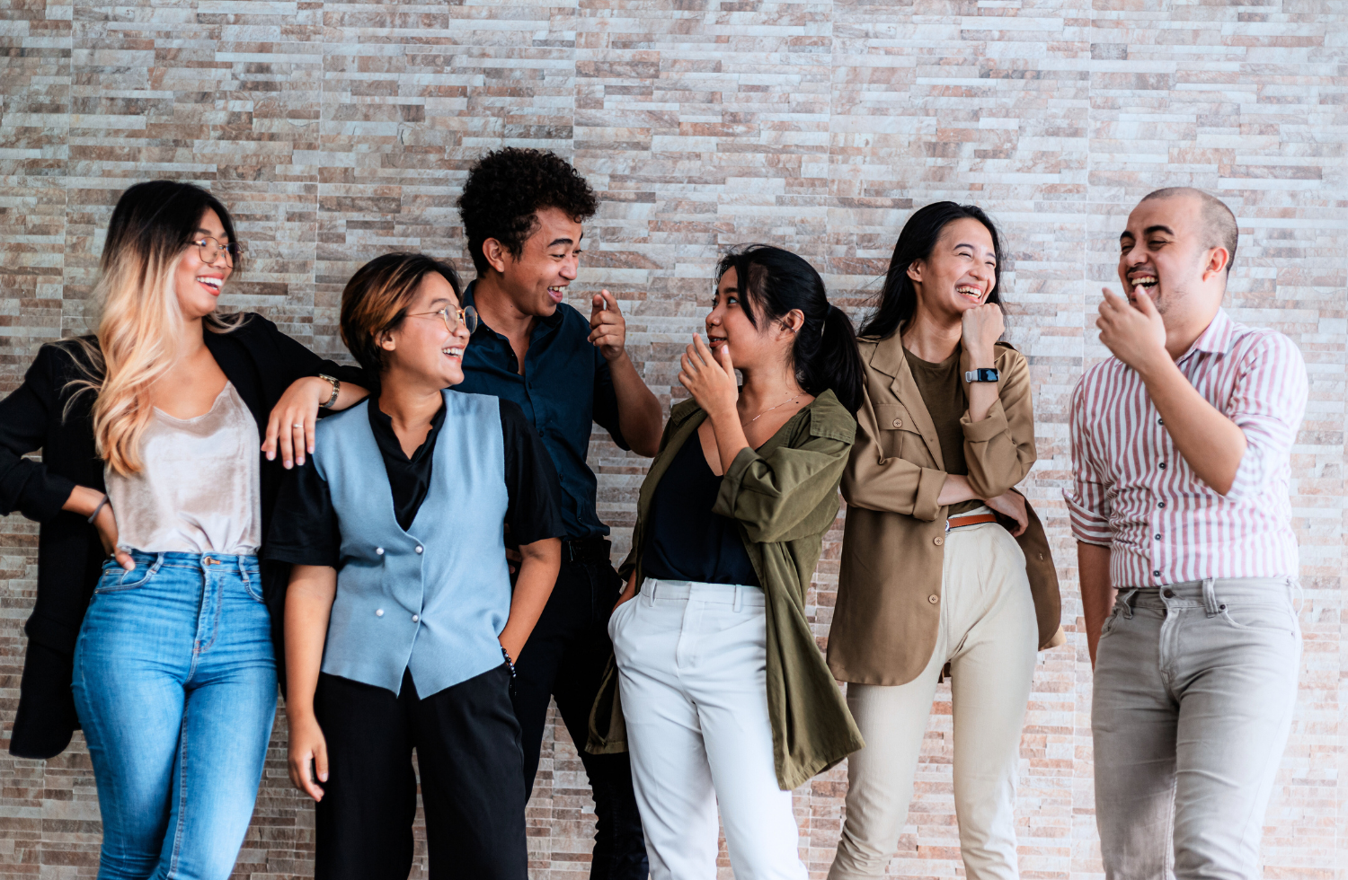 A group of people are standing next to each other in front of a brick wall.
