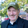 A man wearing a hat and a jacket is smiling for the camera.