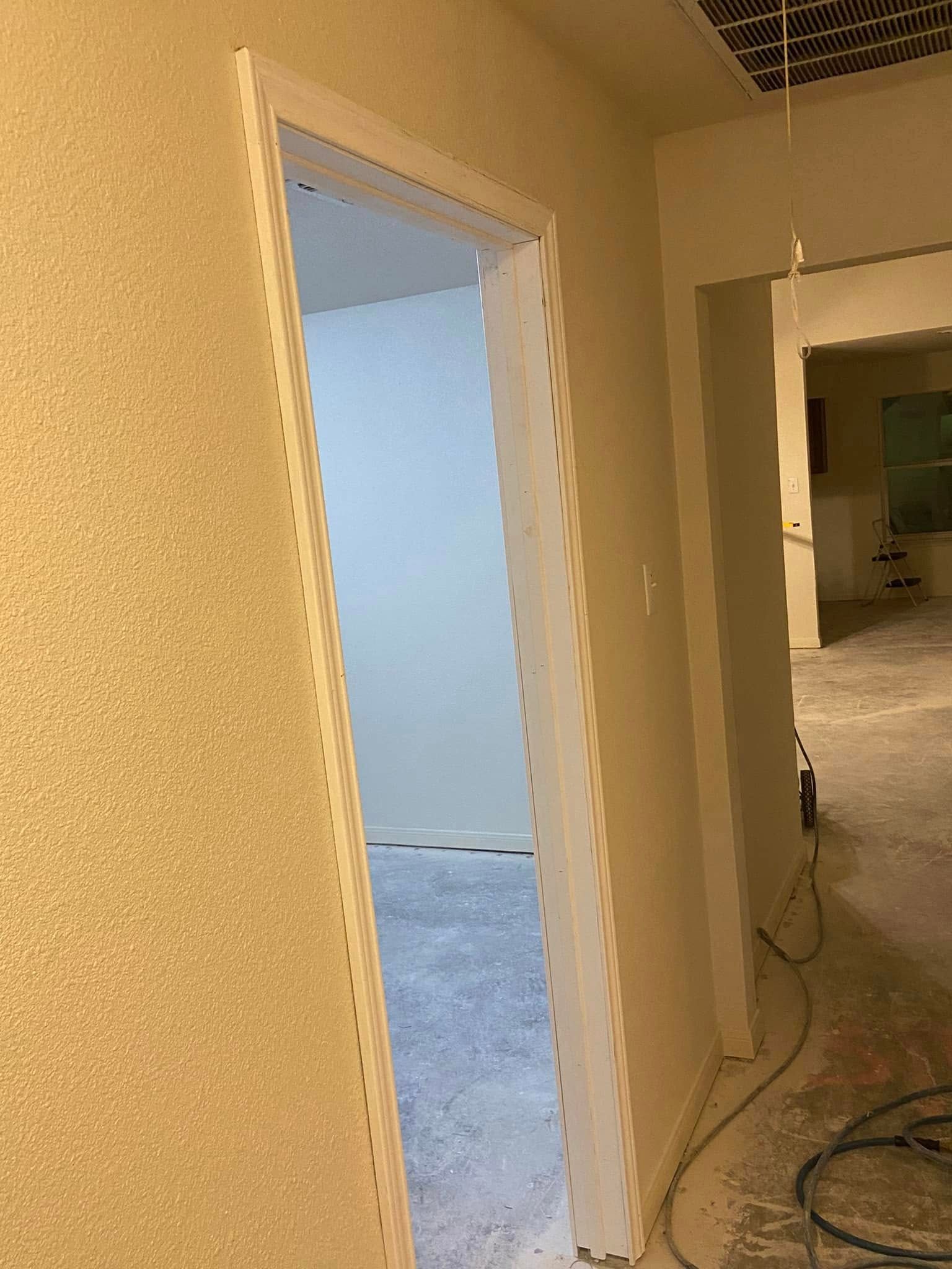 Hallway with doorways; one open to a room with light blue walls, construction in progress.