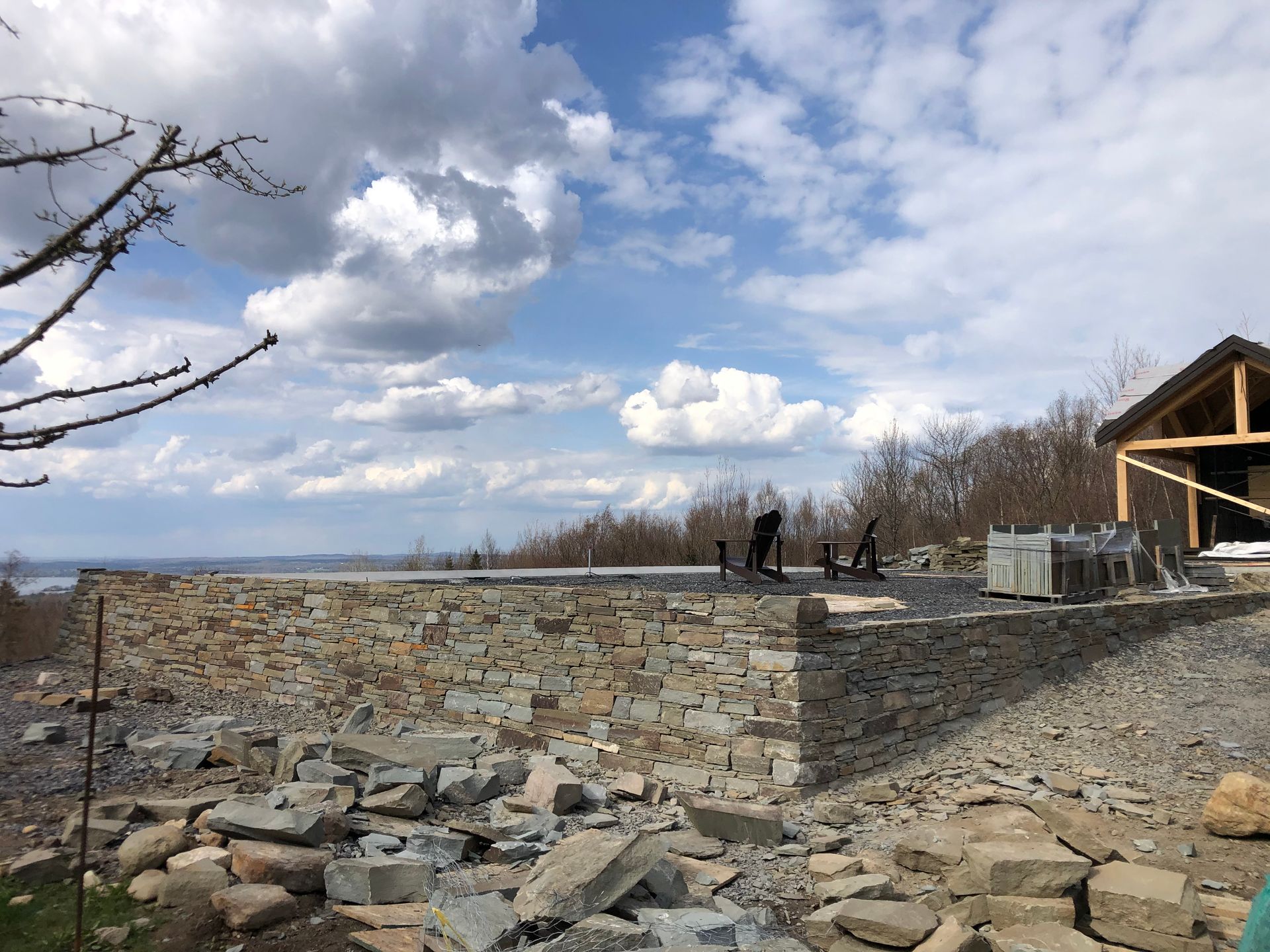 Un grand mur de pierre est en train d'être construit devant une maison.