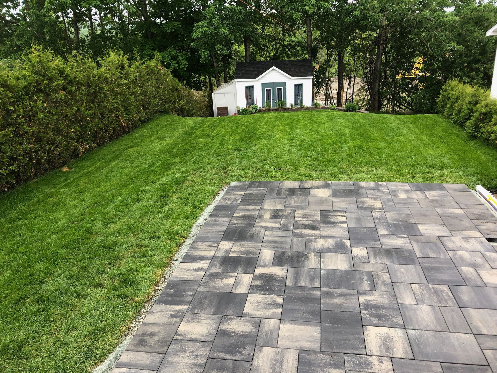 Une allée en briques menant à une maison avec une pelouse verte luxuriante.