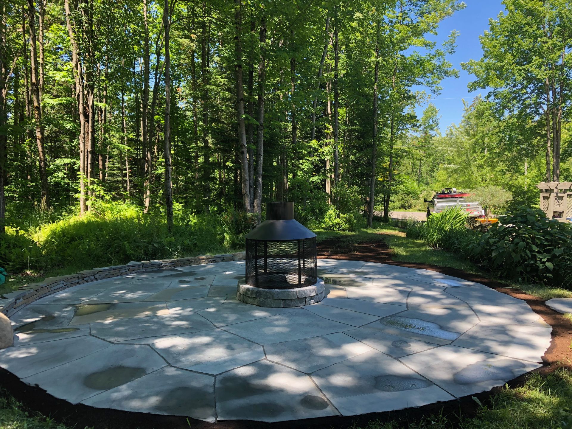 Un patio circulaire avec un foyer au milieu entouré d'arbres.