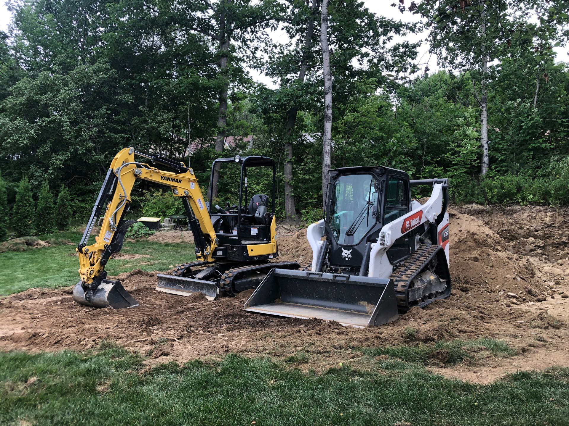 Un bulldozer et une excavatrice sont garés l'un à côté de l'autre dans un champ de terre.