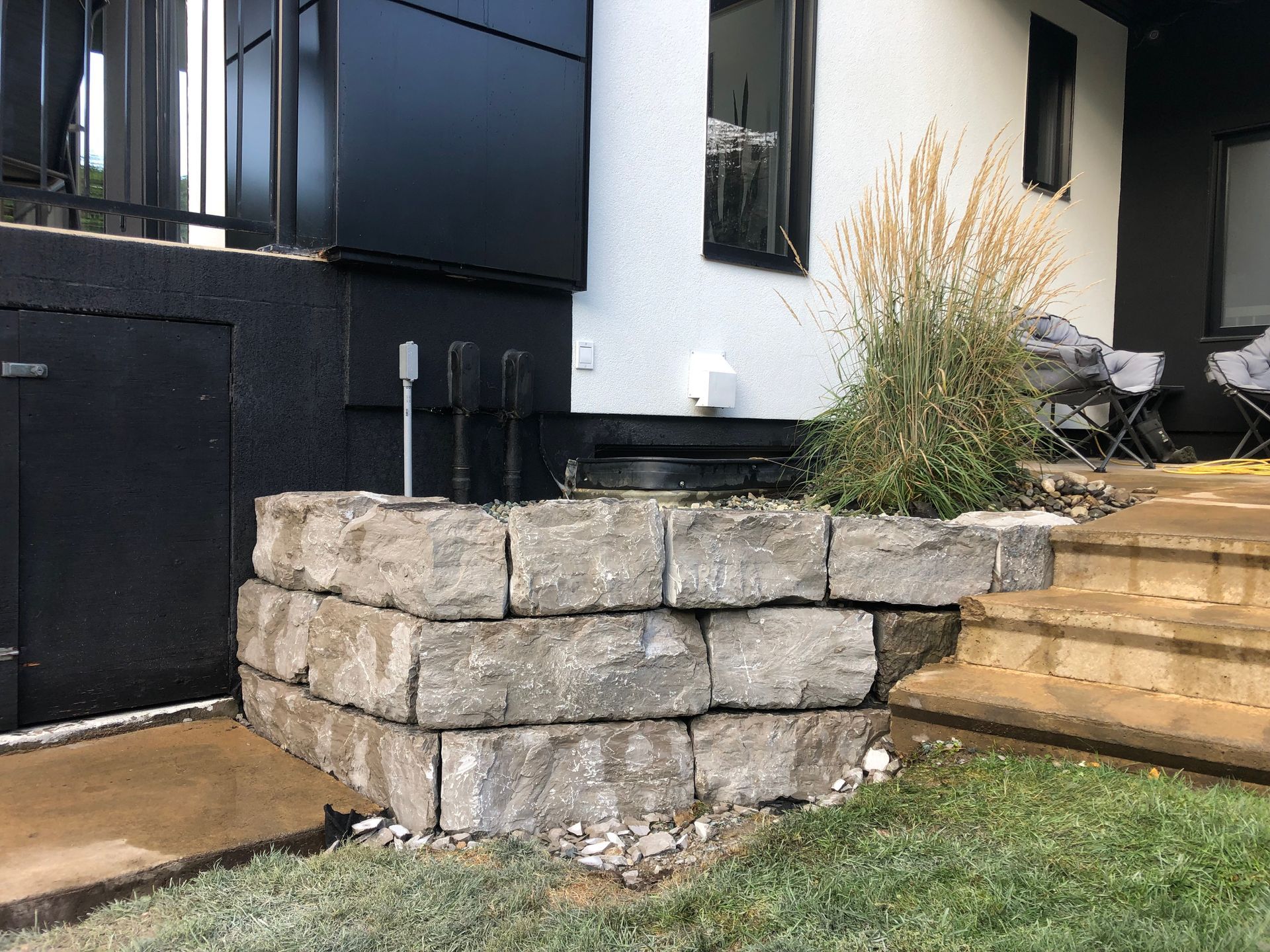 Il y a un mur de pierre devant une maison.