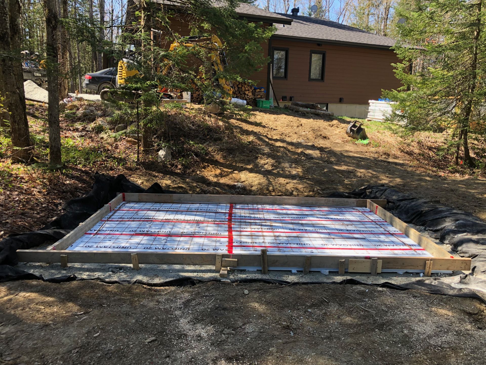 Une maison est assise au sommet d'une colline de terre à côté d'une dalle de béton.