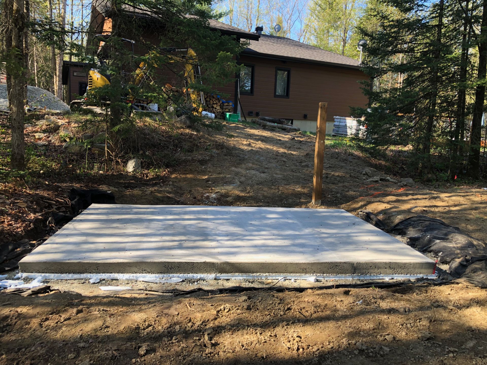 Une grande dalle de béton est posée dans la terre devant une maison.