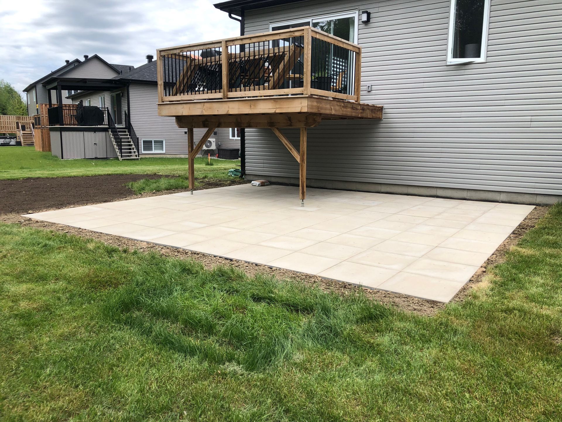 Un grand patio en béton avec une terrasse en bois dans l'arrière-cour d'une maison.
