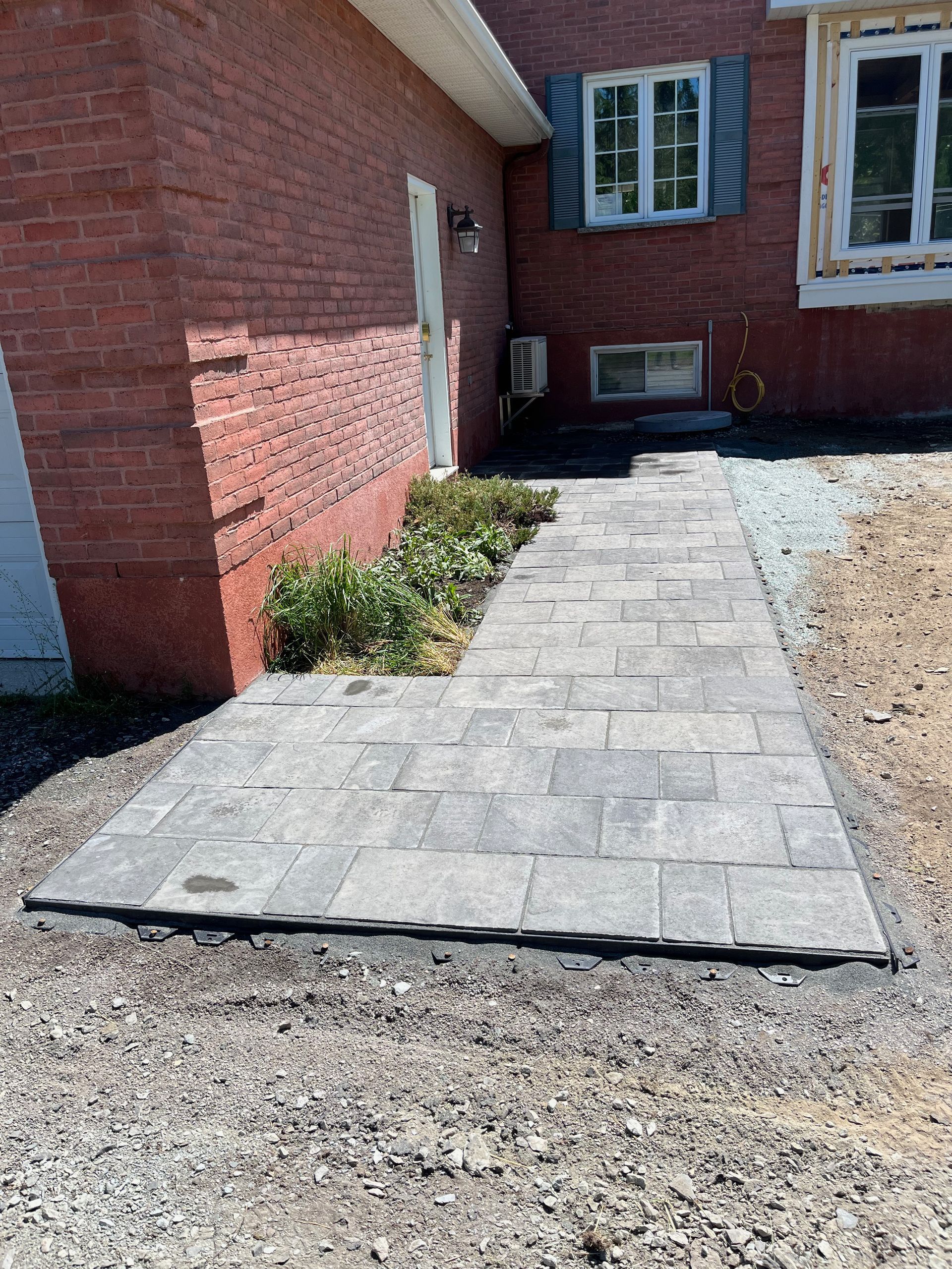 Une passerelle est en cours de construction devant une maison en briques.