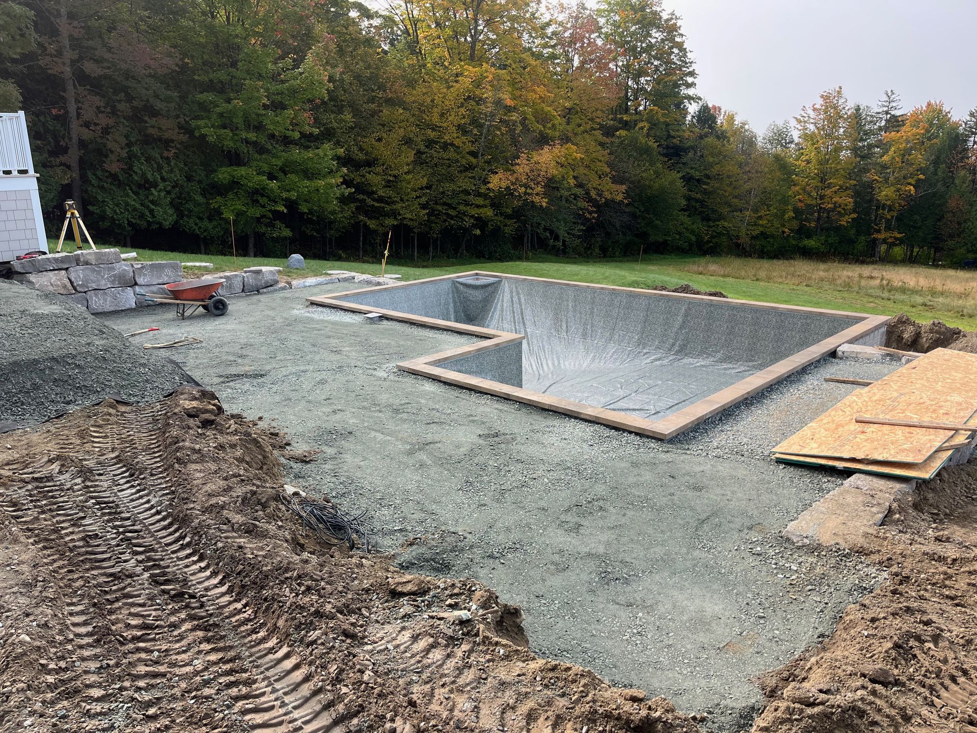 Une grande piscine est en cours de construction au milieu d'un champ de terre.