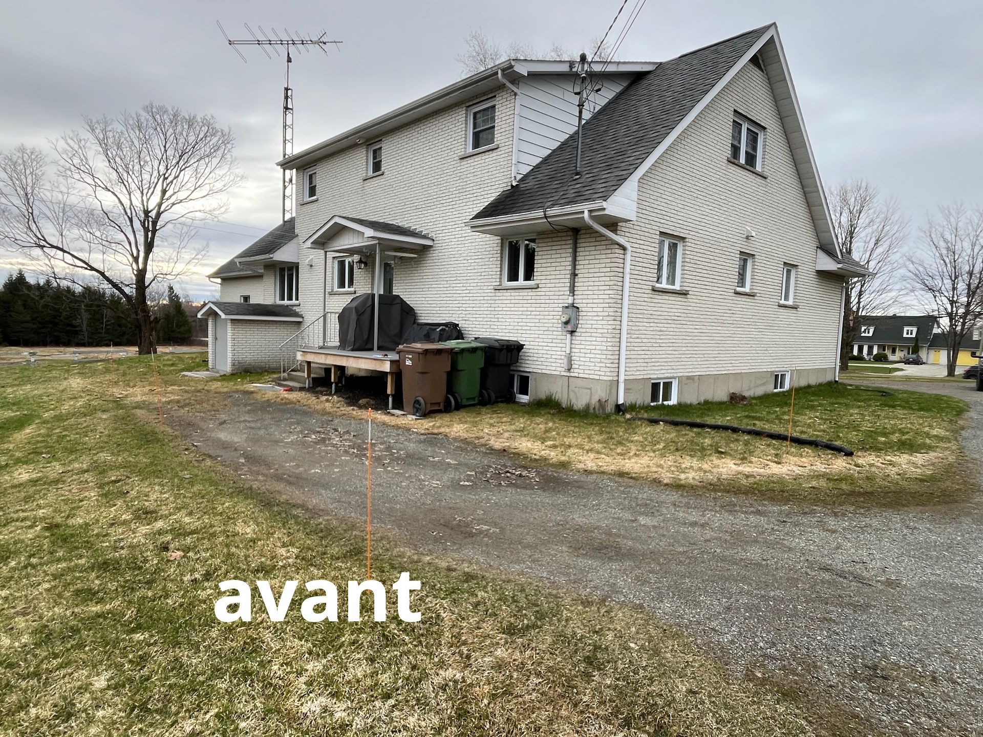Une maison blanche avec un toit noir se trouve au milieu d'un champ herbeux.