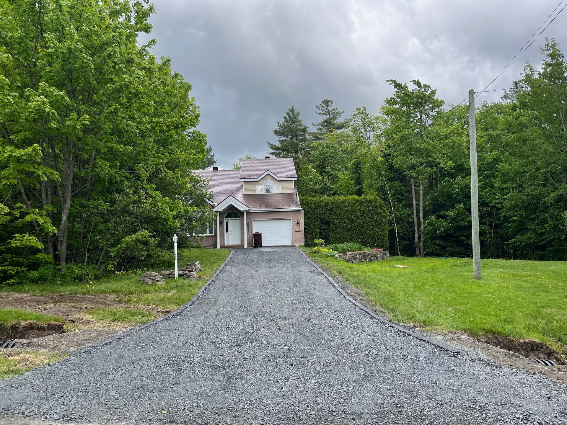 Une allée de gravier menant à une maison entourée d'arbres.