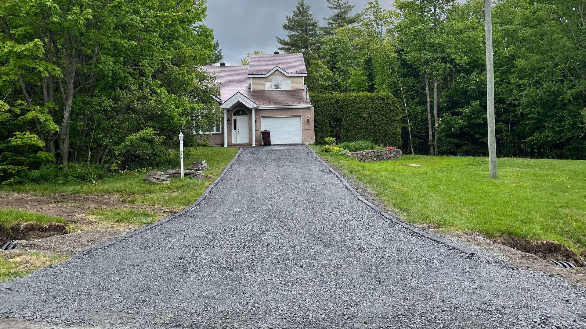 Une allée de gravier menant à une maison avec un garage.