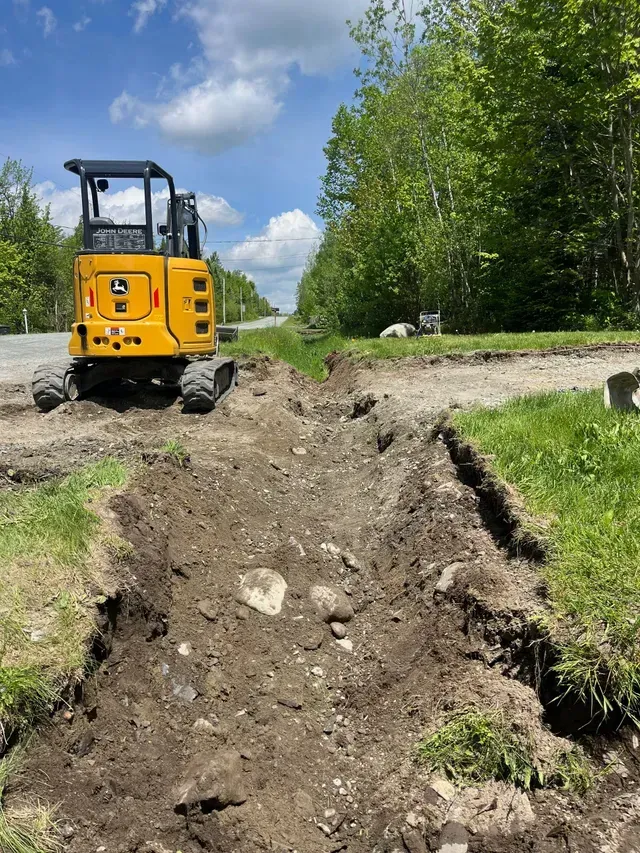 Une excavatrice jaune creuse un trou dans le sol.