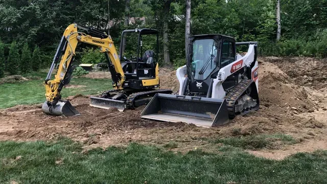 Un bulldozer et une excavatrice sont assis au sommet d'une colline de terre.