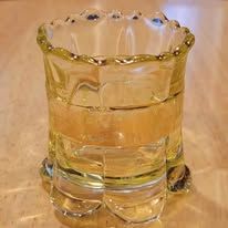 Yellow glass tumbler with ornate rim and base, on a light-colored surface.