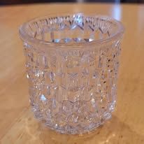 Clear, textured glass toothpick holder on a wooden surface.