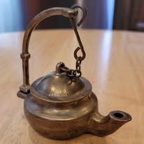 Antique bronze miniature oil lamp with handle and spout.