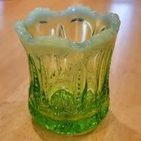 Green and yellow glass toothpick holder with a scalloped rim.