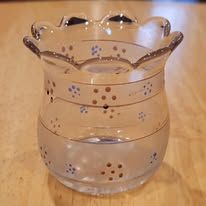 Clear glass vase with a ruffled rim, decorated with gold lines and blue/brown dots.