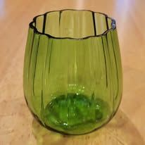 Green ribbed glass vase on a wooden surface.