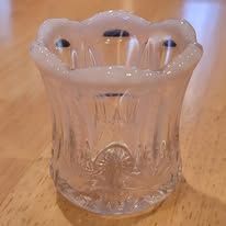 Clear glass toothpick holder with a pinkish-white ruffled rim and floral etched pattern.