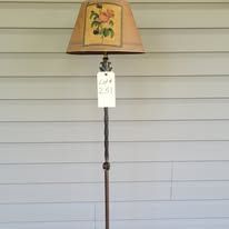 Floor lamp with floral lampshade, metal stem, and auction tag against a white wall.