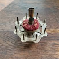 Antique metal sewing tool with pin cushion and spool holder.