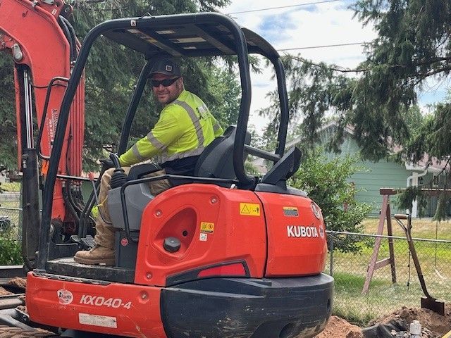 a man is sitting on a red kubota excavator — North Branch, MN — Hassle Free Septic