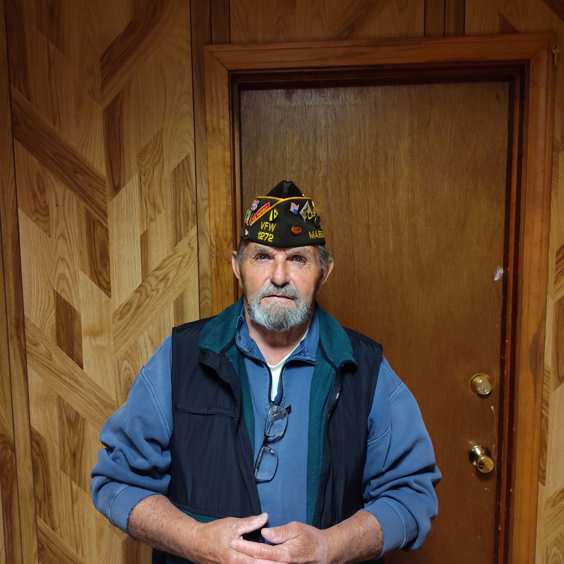 A man wearing a hat and vest is standing in front of a door