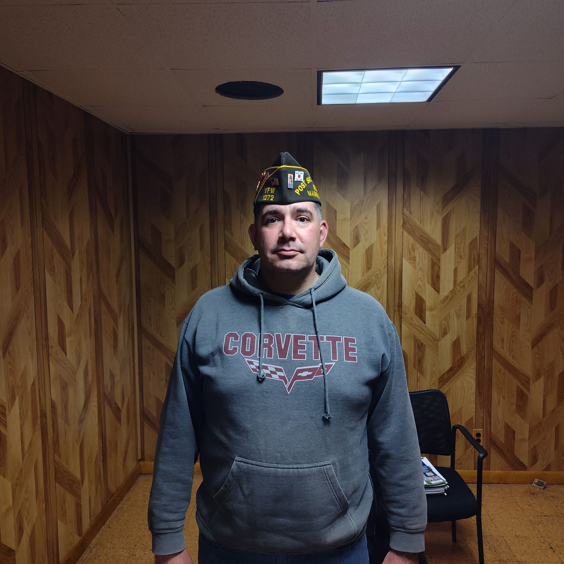 A man wearing a corvette sweatshirt and a hat