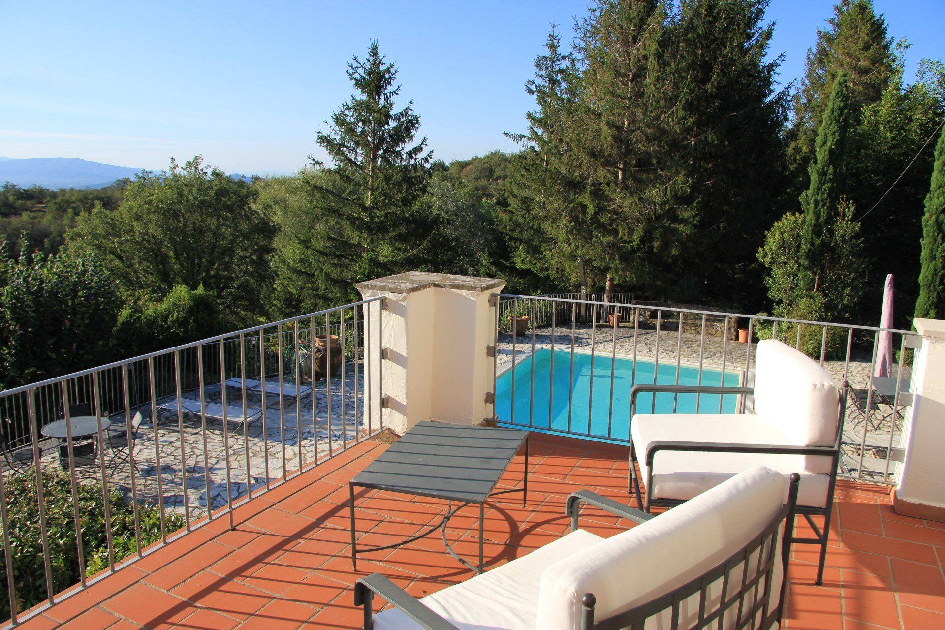 Zicht op stoelen op het balkon met zwembad in de achtergrond