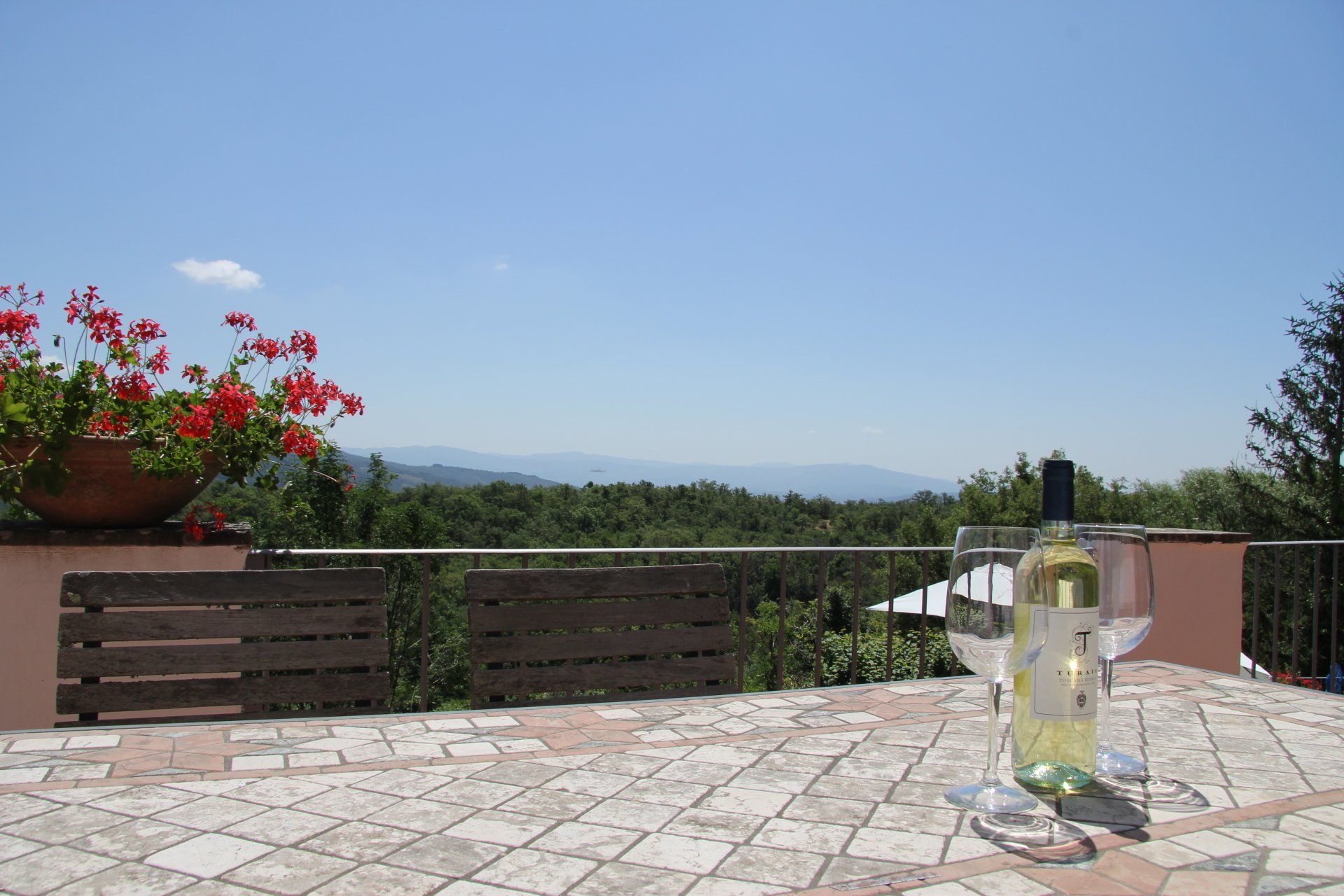 Tafle op het balkon met fles en glas wijn met uitzicht op de vallei