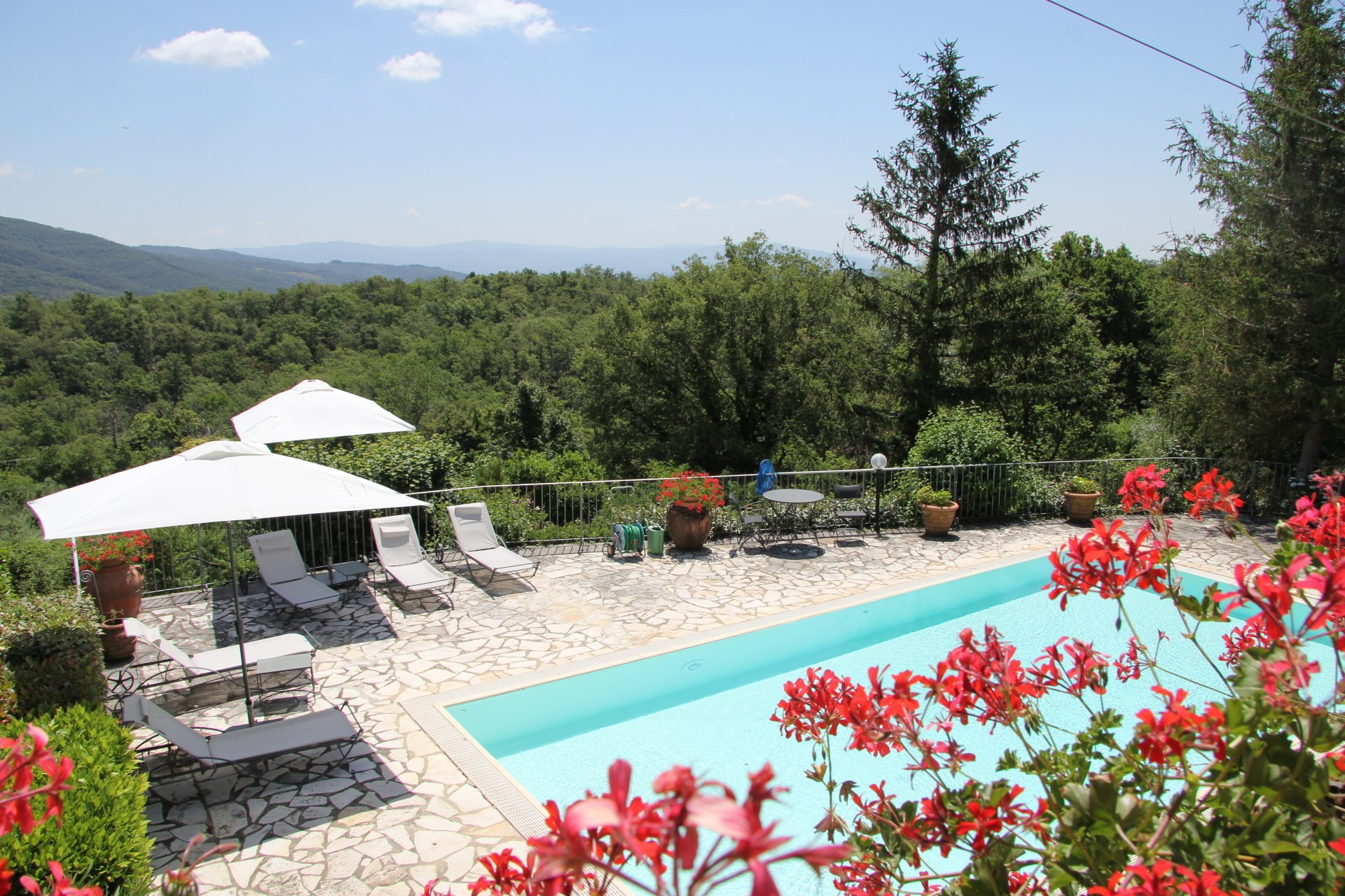 Zicht vanaf het balkon op het zwembad met parasols