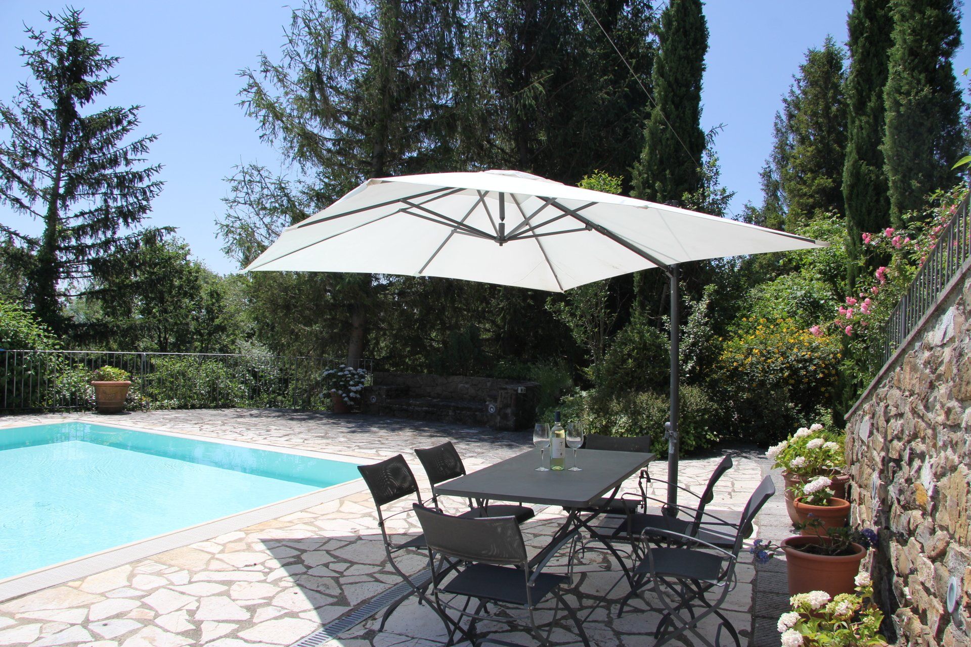 Eettafel onder de parasol met zwembad op de achtergrond