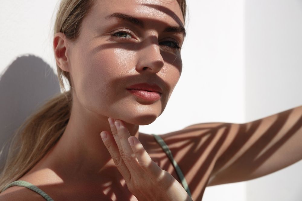 A close up of a woman 's face with a palm tree shadow on her face.