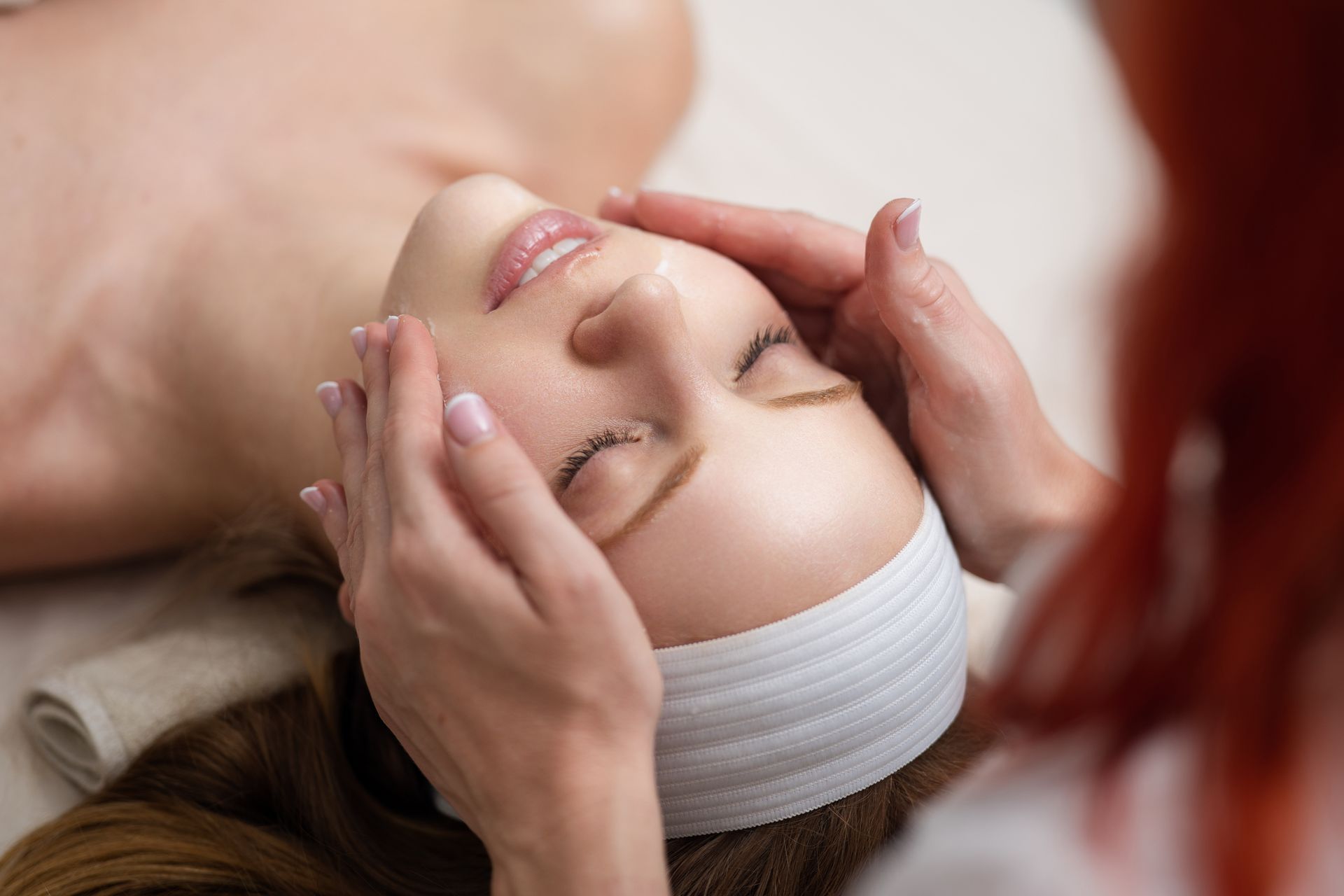 A woman is getting a facial massage at a spa.