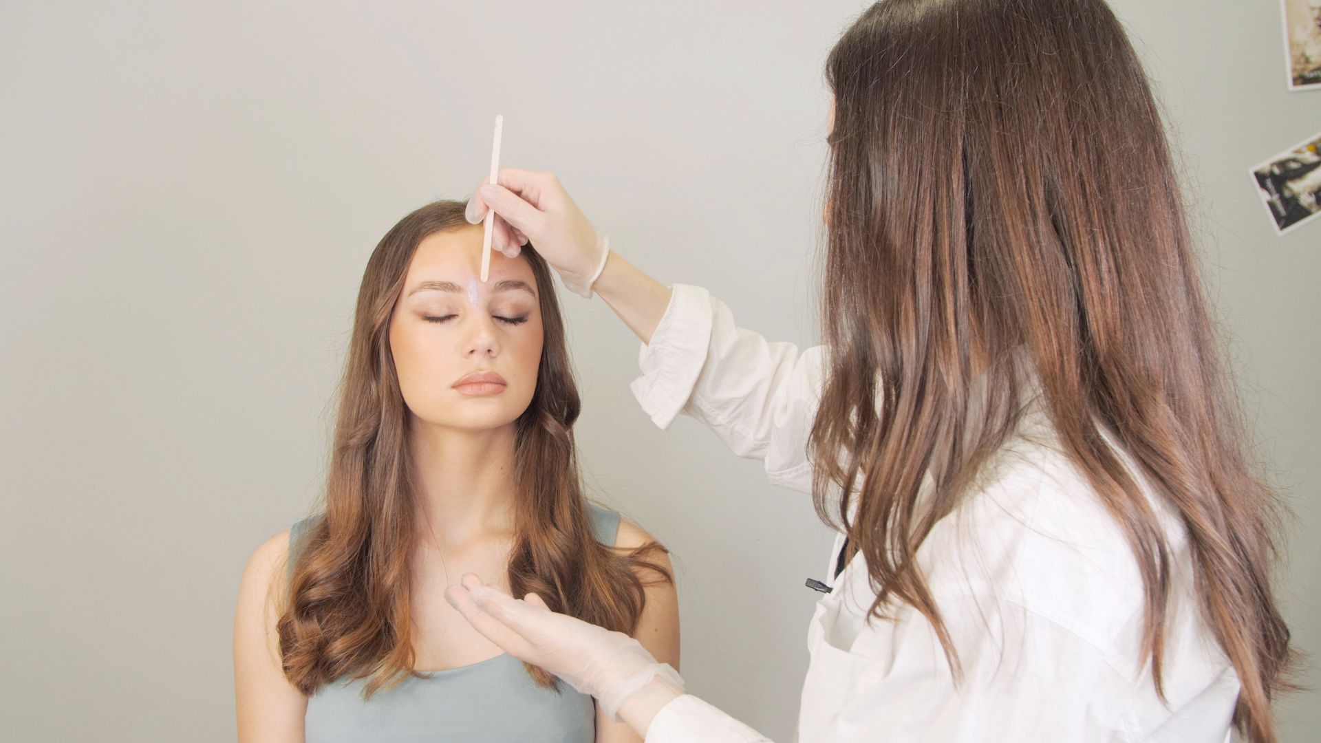 A woman is getting her eyebrows measured by a doctor.