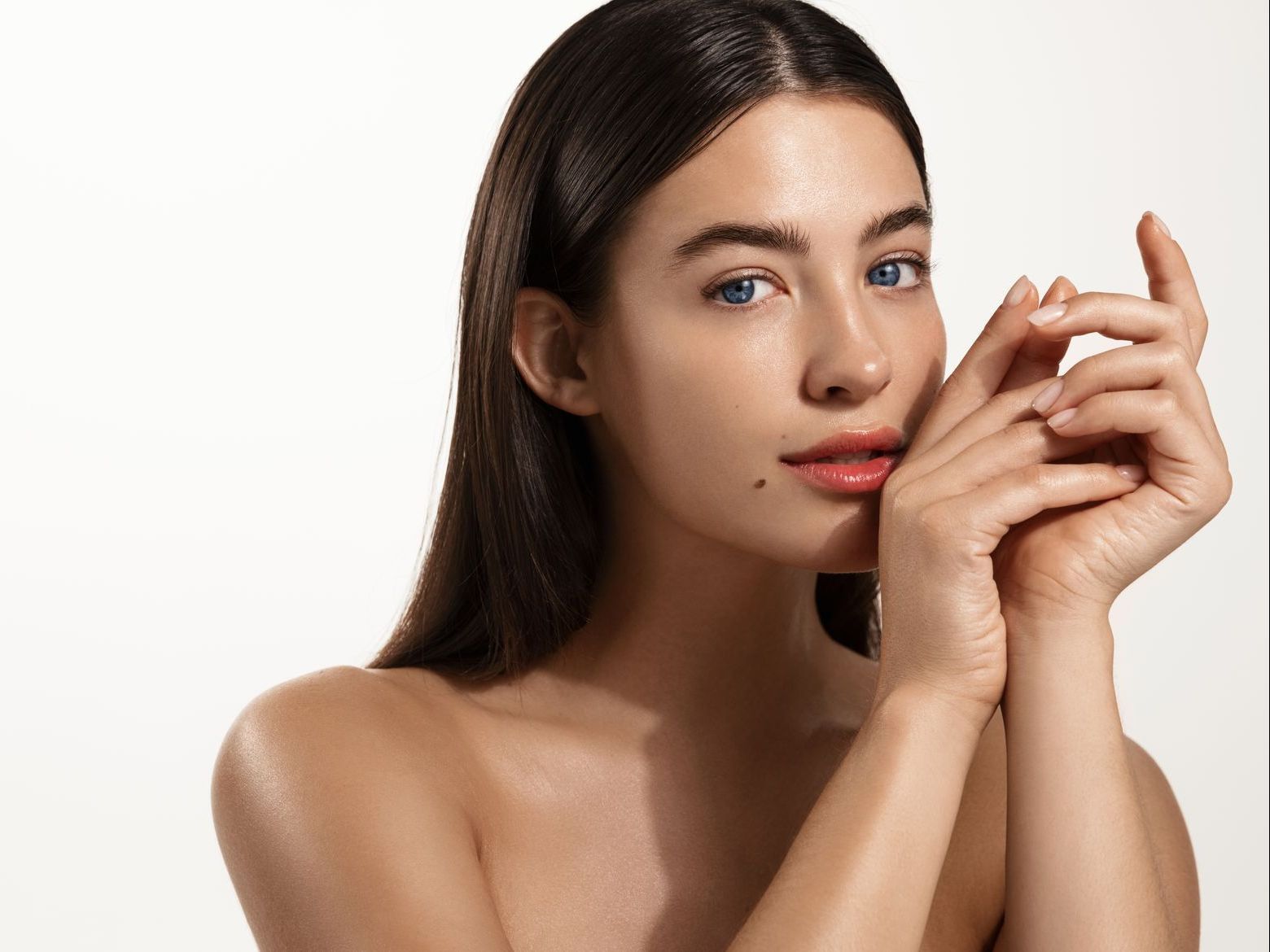 A woman is looking into the camera while holding her hands together. 