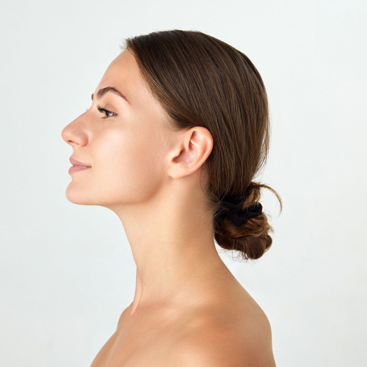 A close up of a woman 's face with her hair in a bun.