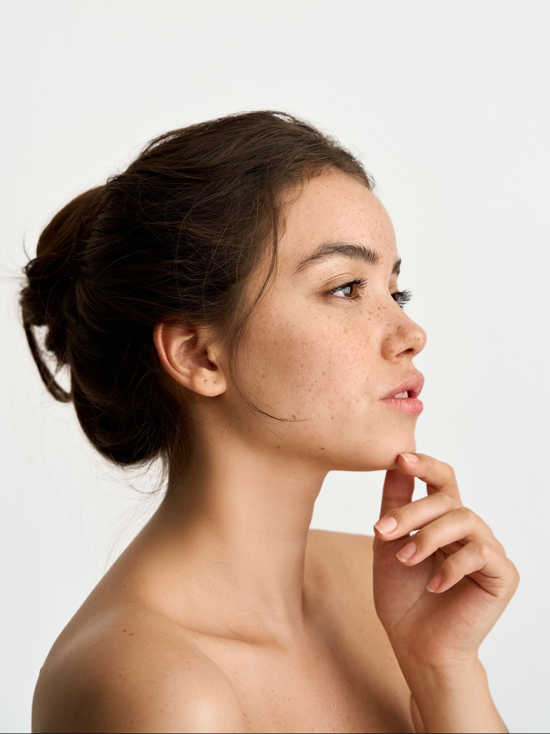 A close up of a woman 's face with her hand on her chin.
