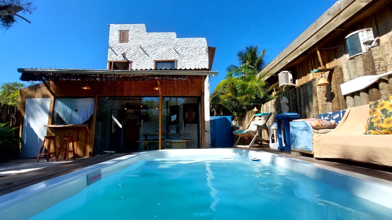 Uma grande piscina fica em frente a uma casa. Pousada Quadradinho de Trancoso