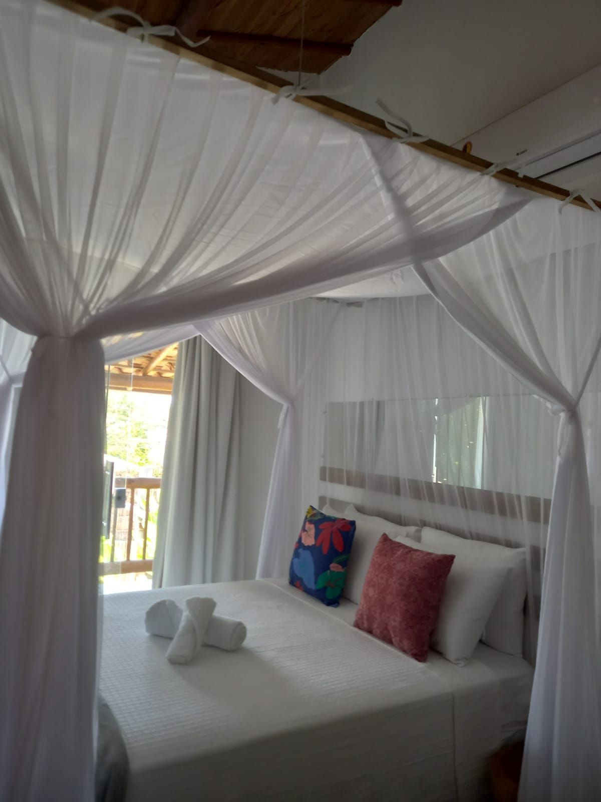 Um quarto com uma cama de dossel e cortinas brancas Pousada Quadradinho de Trancoso