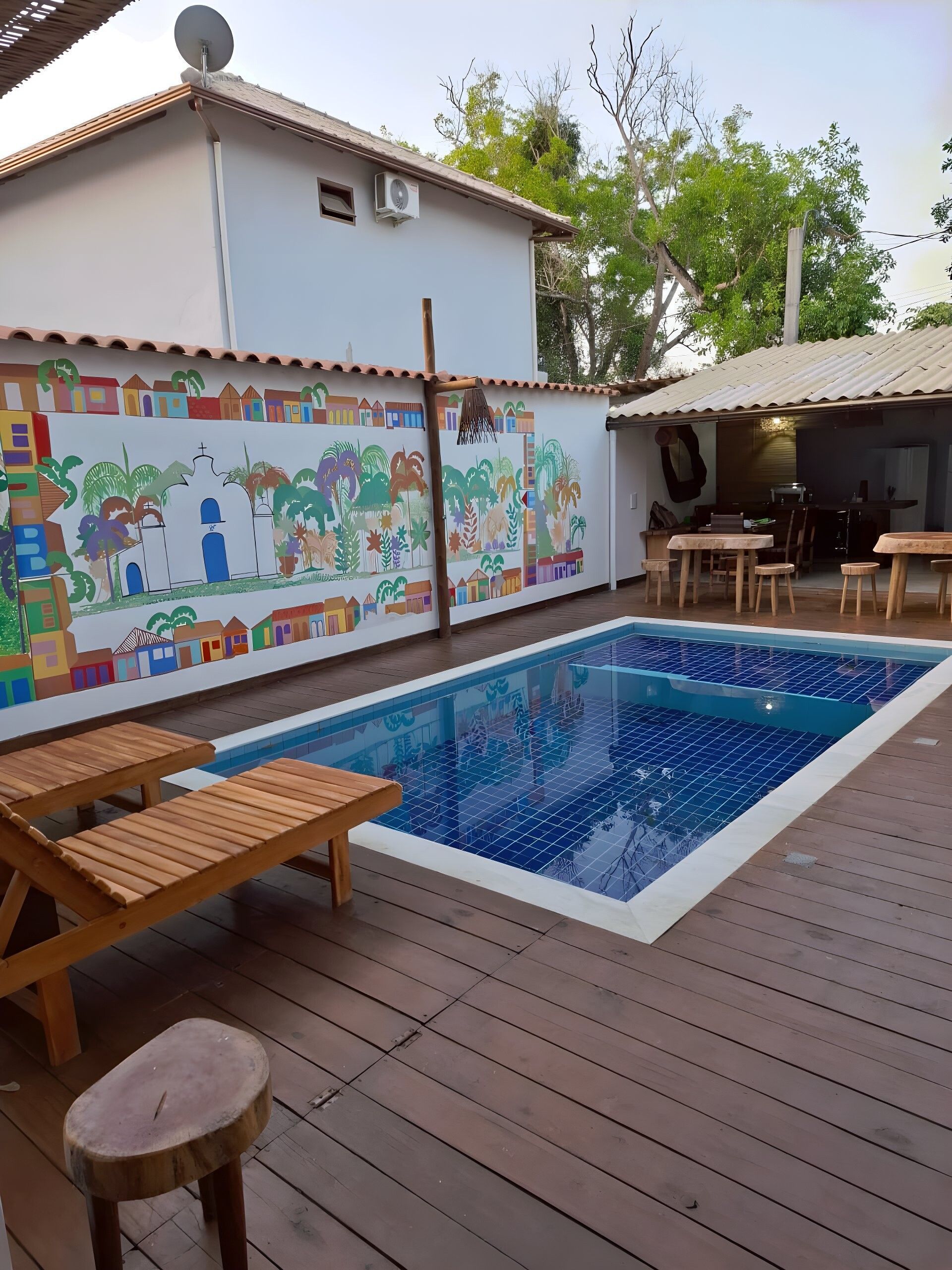 Uma grande piscina cercada por cadeiras e mesas Pousada Quadradinho de Trancoso