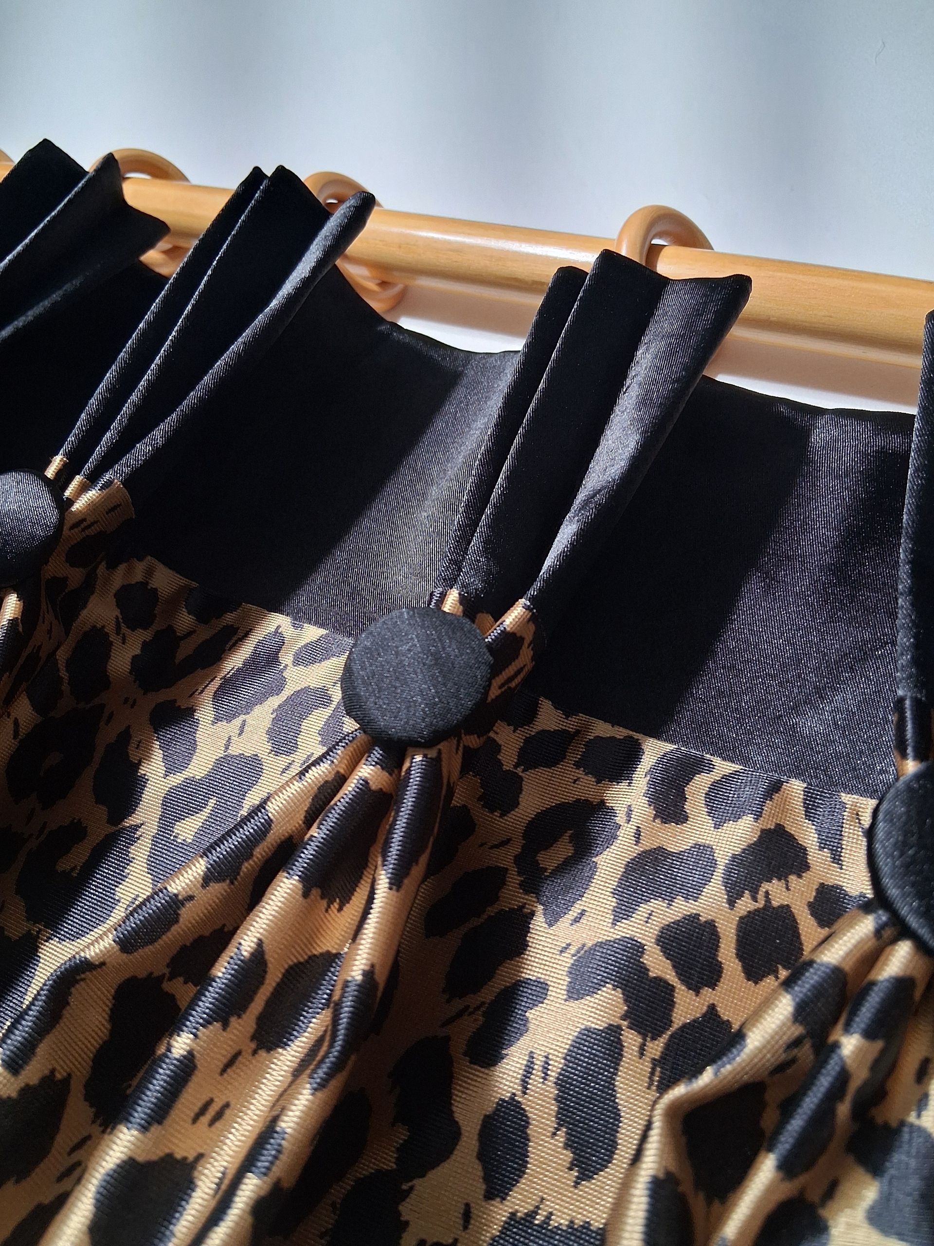 Leopard-print dress with black shoulder straps hanging on a wooden rack