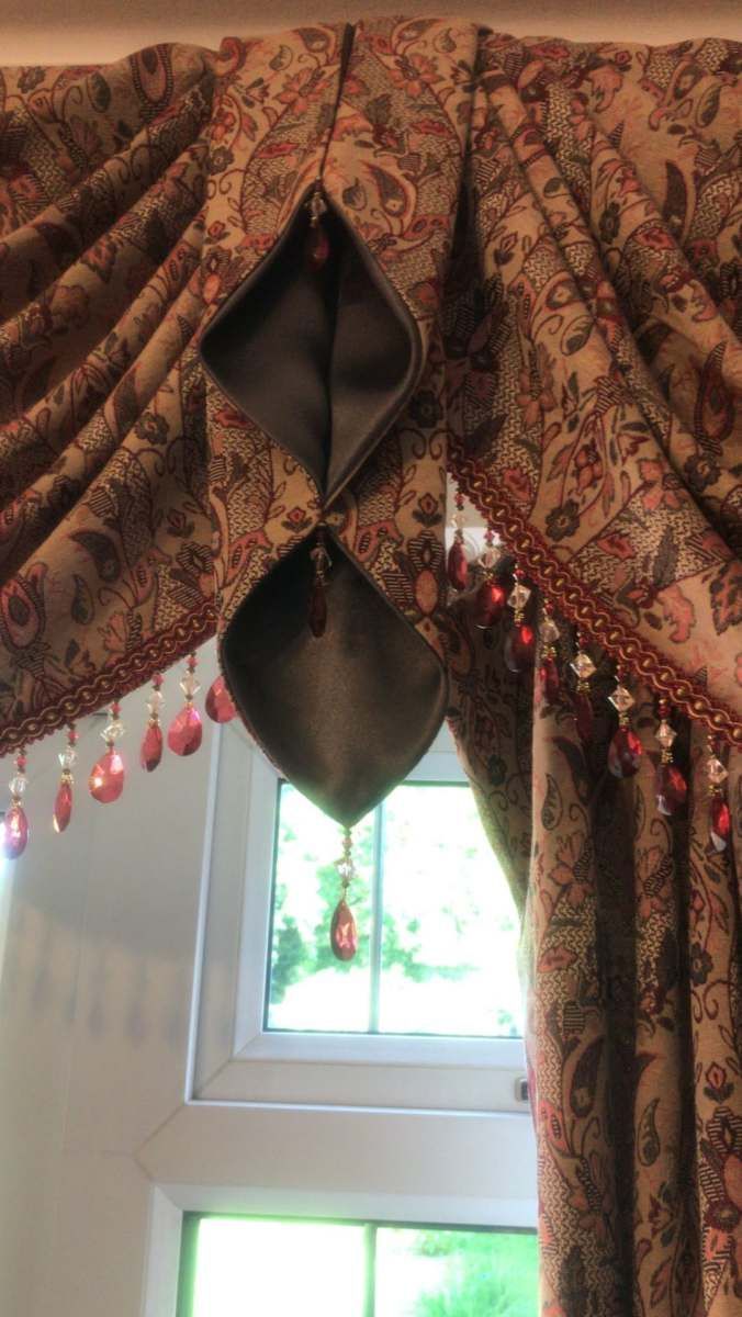 Patterned curtain valance with hanging beads above a sunlit window
