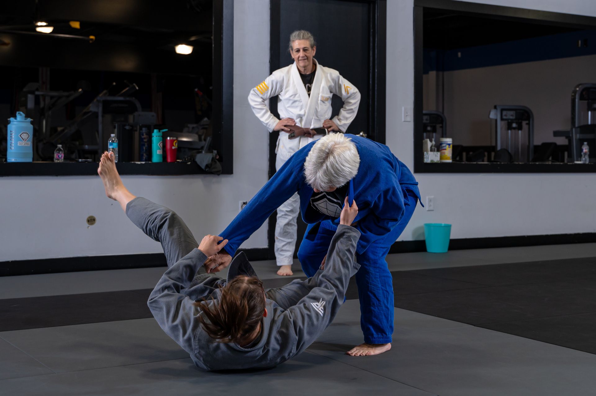 A man and a woman are practicing jiu jitsu in a gym.