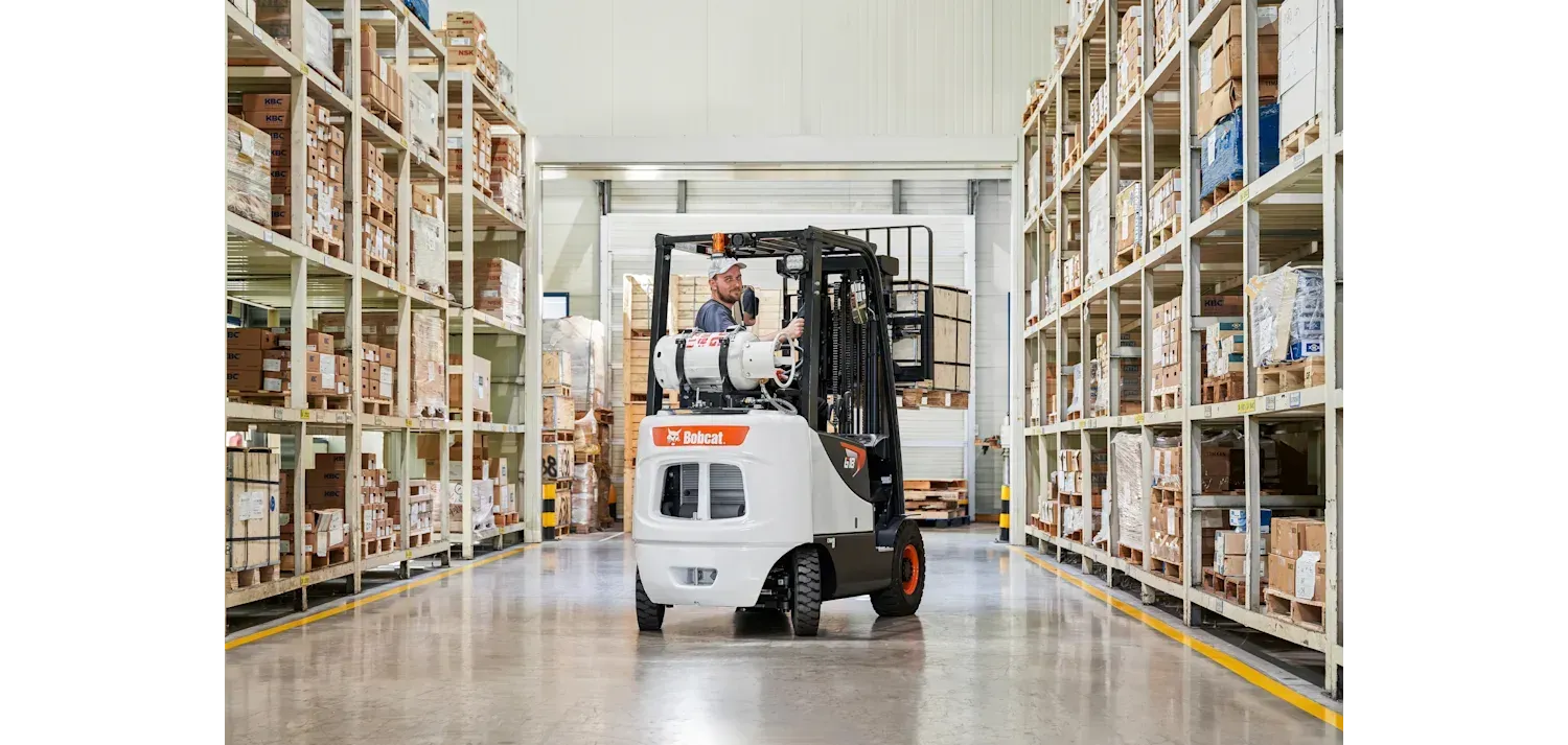 A man is driving a forklift in a warehouse.