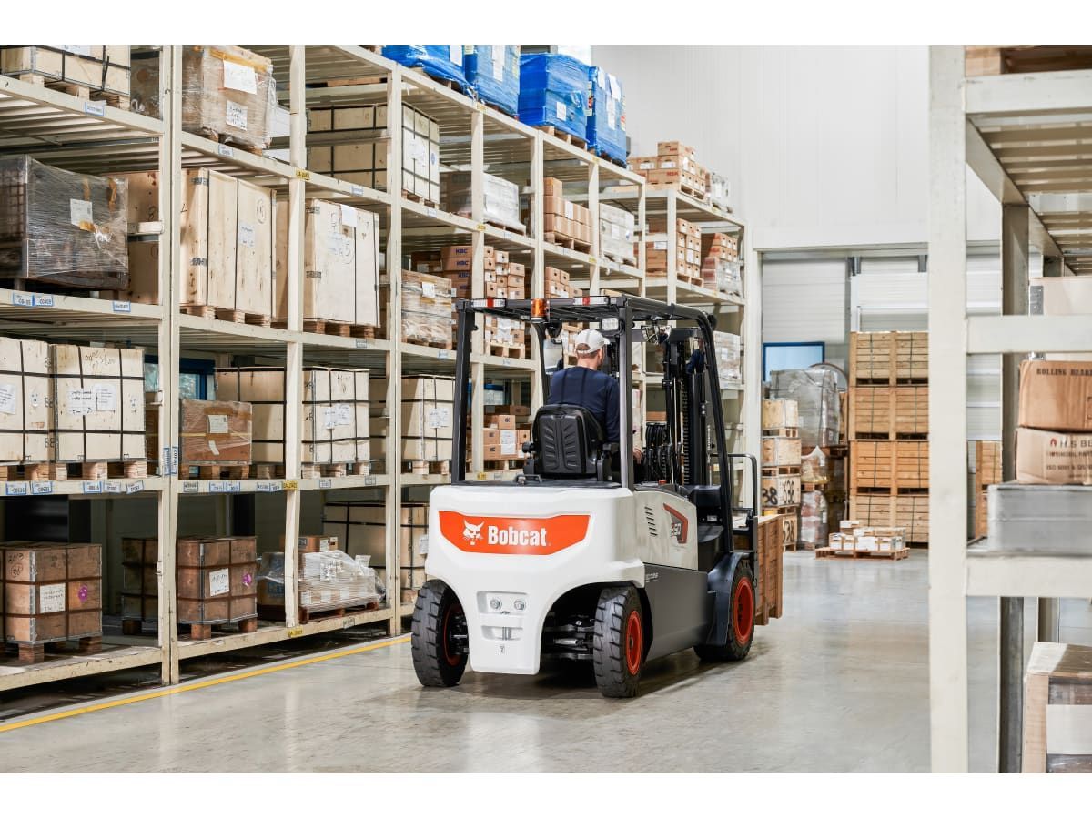 A man is driving a forklift in a warehouse.